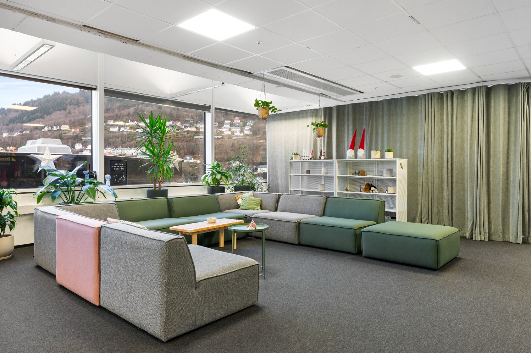 The HUB Social Area lounge with modular sofas, plants and a view of the Bergen hills.