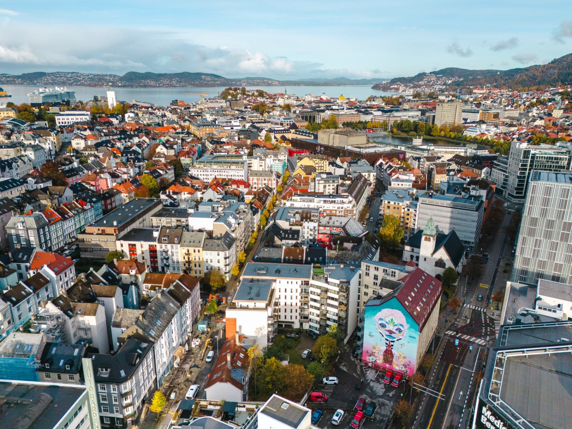 Aerial view over central Bergen showing rooftops, the fjord and mountains.
